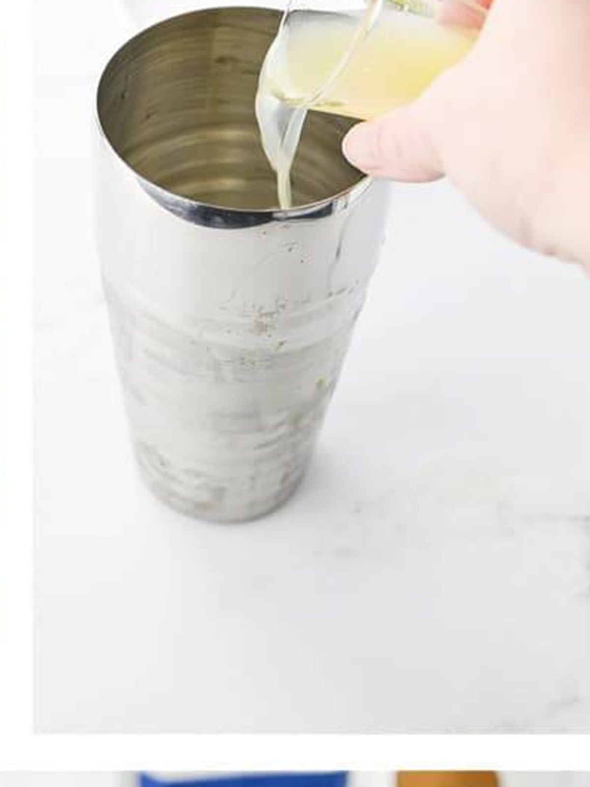 Fresh lime juice being poured into the cocktail shaker with the tequila.