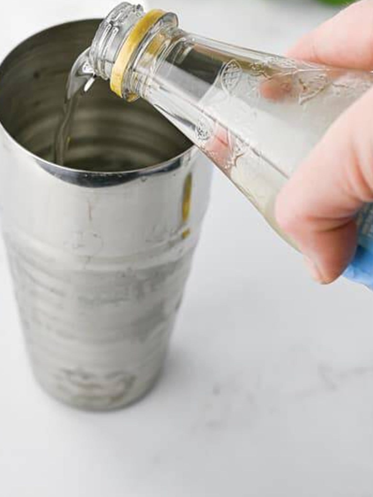 Simple syrup being poured into the cocktail shaker to finish the margarita.