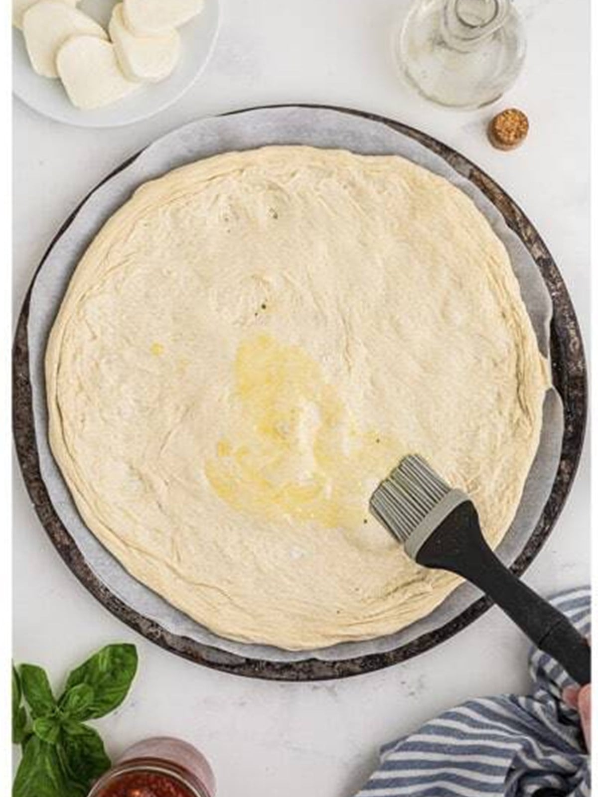 Brushing olive oil over stretched pizza dough