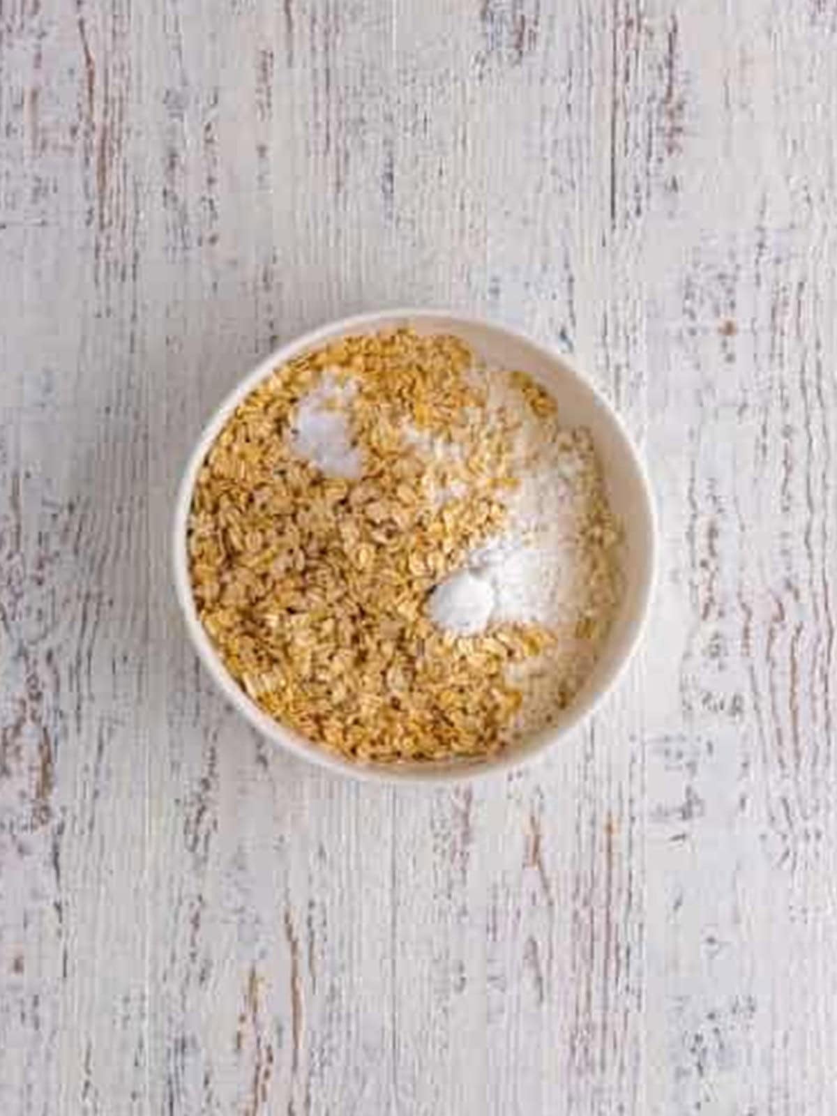 Flour and rolled oats stirred together in a bowl for monster cookie bars.