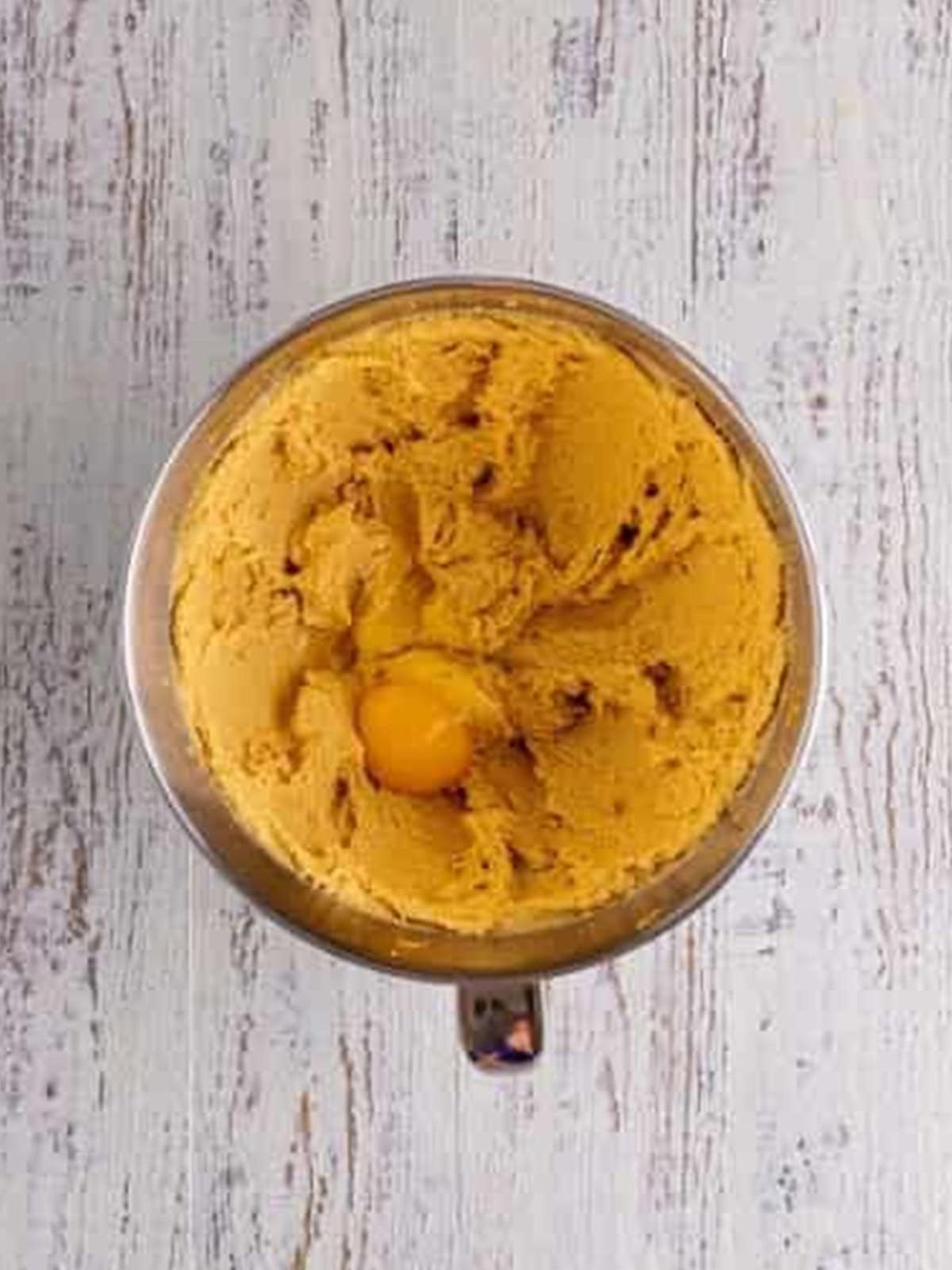 Eggs being added to the creamed butter, peanut butter, and sugar.