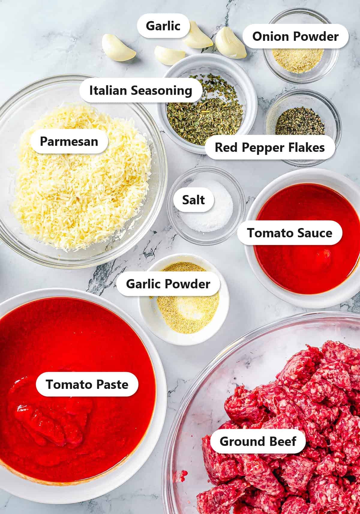 Labeled ingredients to make meat sauce including ground beef, tomato sauce, tomato paste, parmesan, garlic, italian seasoning, red pepper flakes, garlic powder, onion powder, and salt.