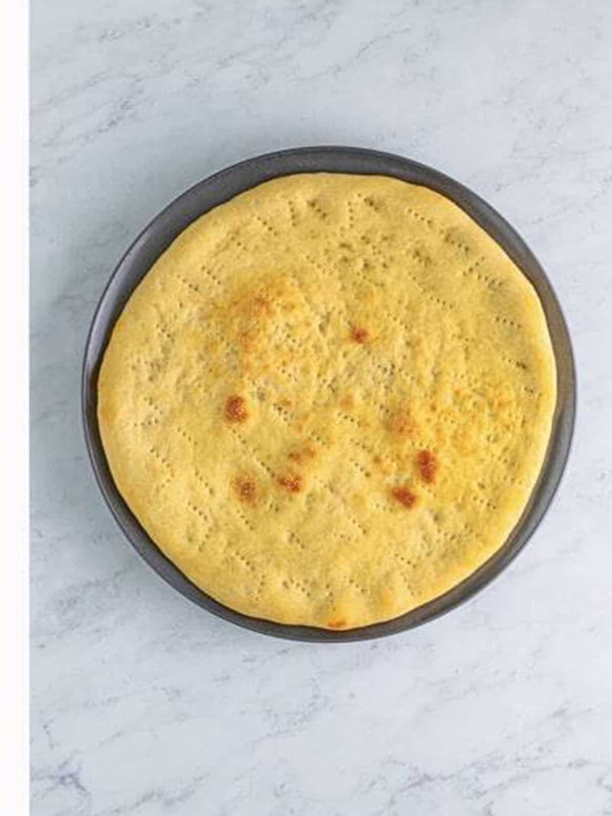 A par-baked pizza crust on a pizza pan.