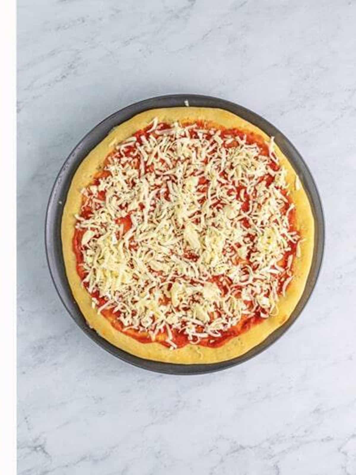 Pizza sauce and shredded mozzarella spread over the crust.