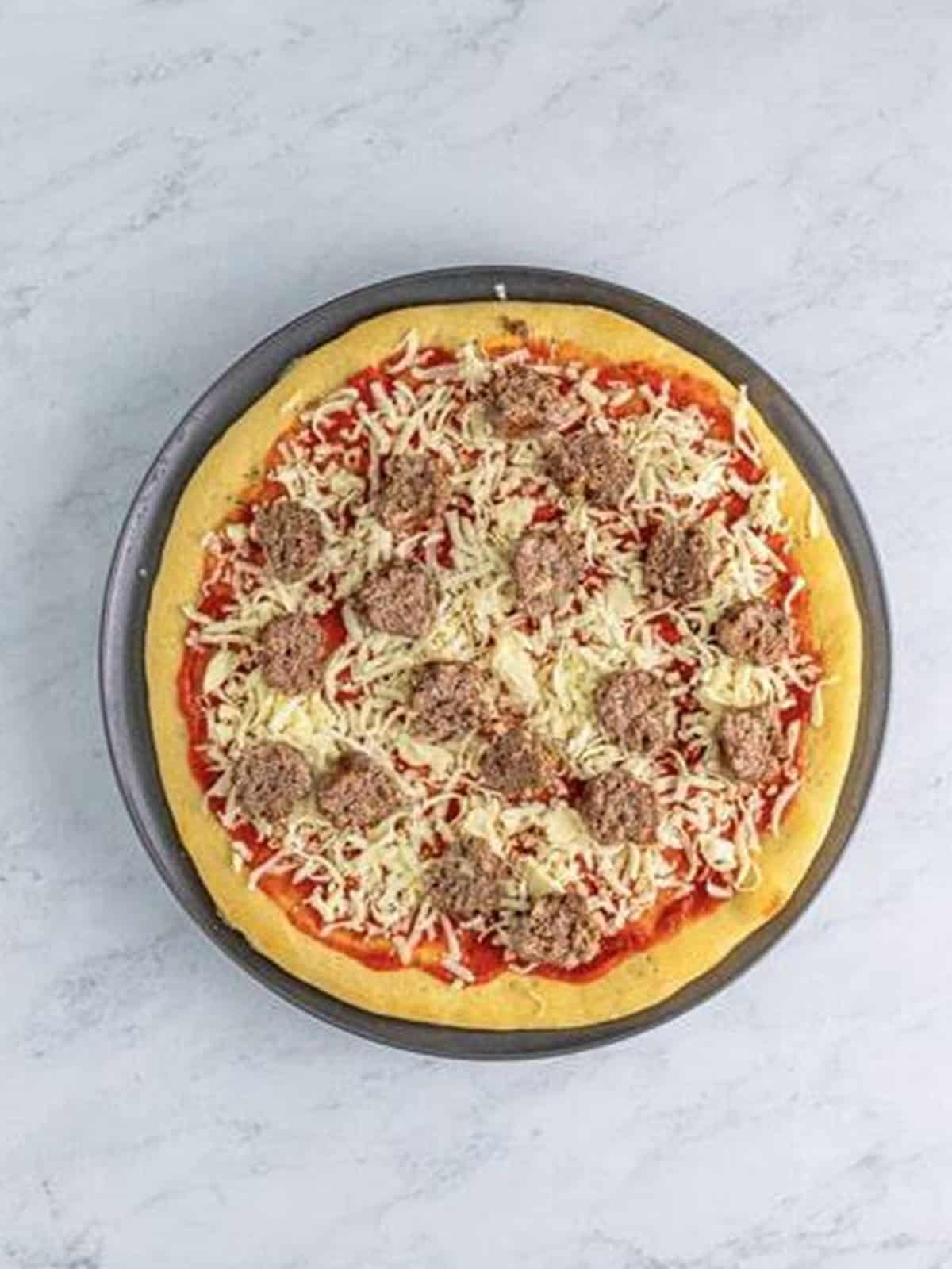 Halved meatballs and cheese layered on the meatball pizza.