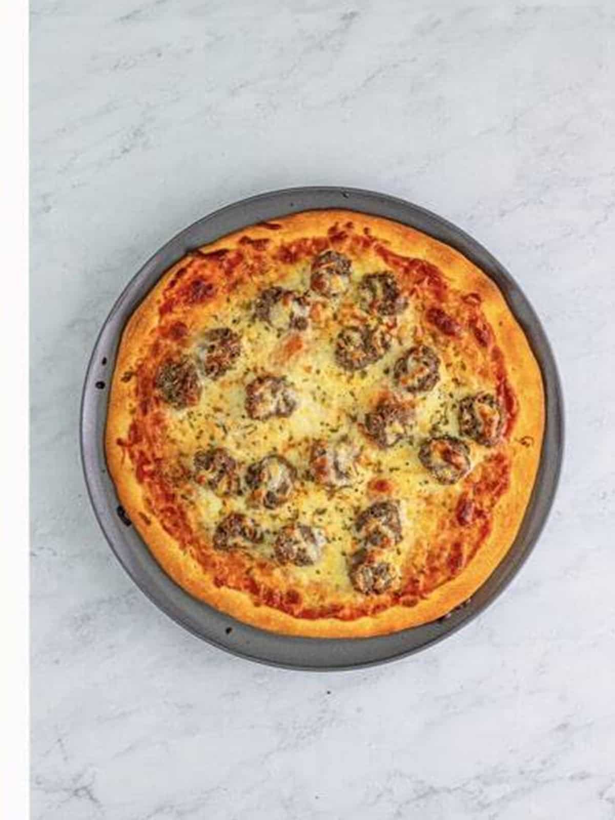 A finished golden meatball pizza fresh out of the oven.