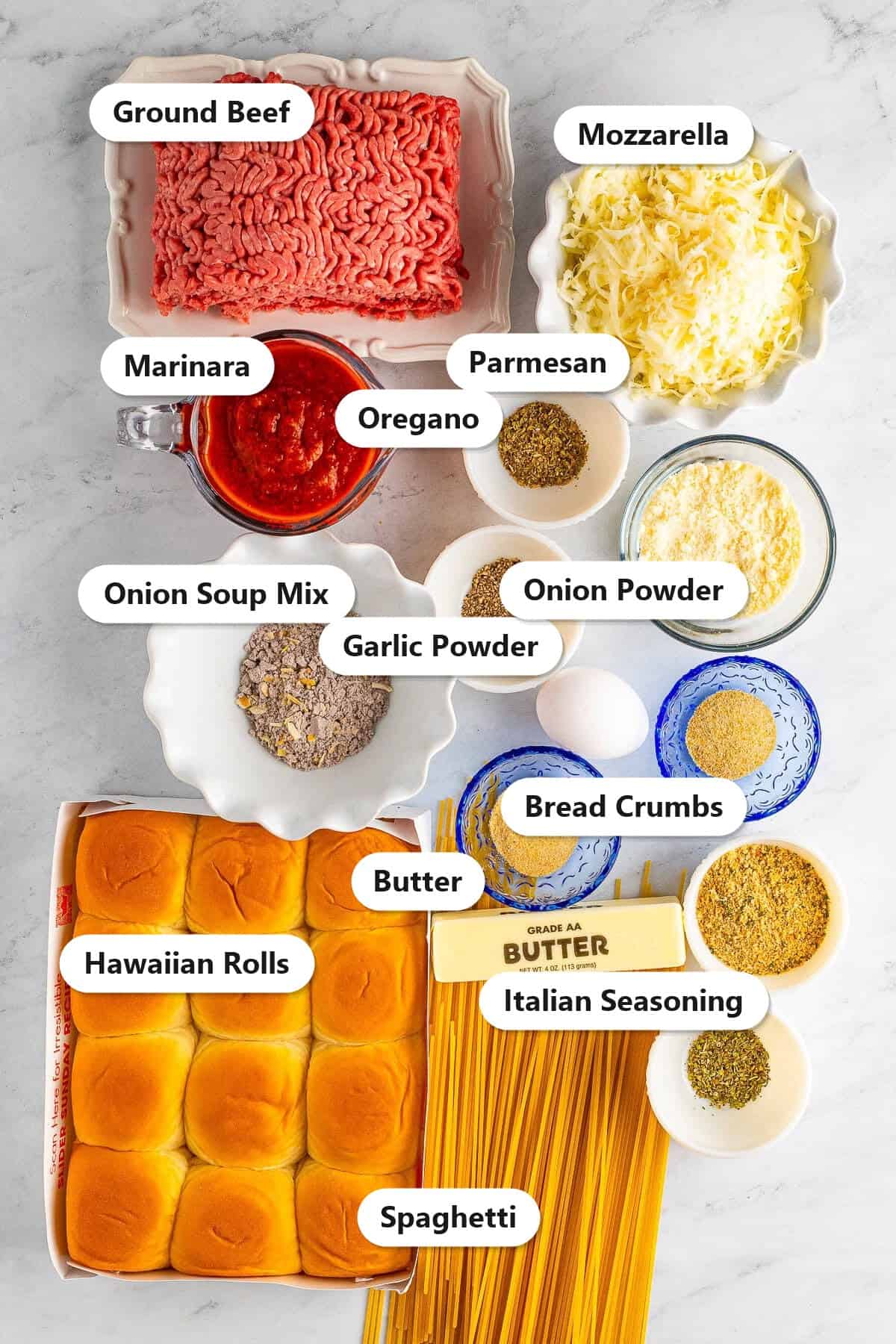 Labeled ingredients to make spaghetti and meatball sliders including ground beef, Hawaiian rolls, spaghetti, marinara, mozzarella, parmesan, butter, and seasonings.