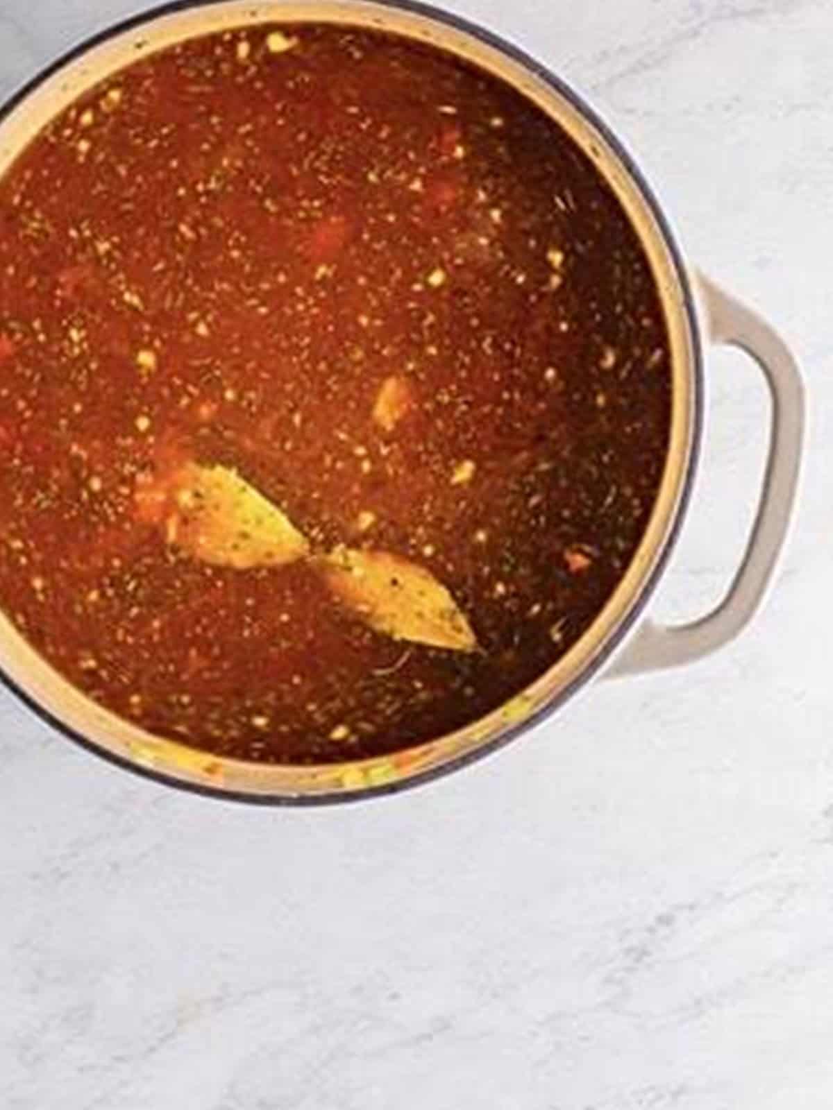 Beef stock, diced tomatoes, and tomato sauce added to a soup pot.