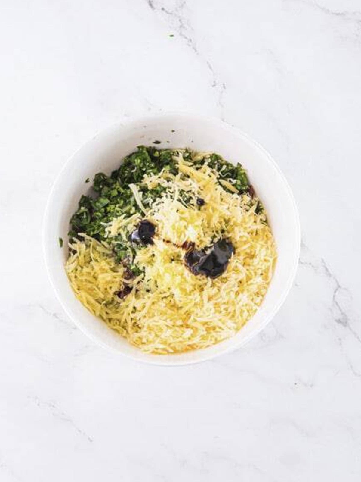 Sun-dried tomatoes, herbs, olives, and parmesan layered in a bowl for Mediterranean dip.