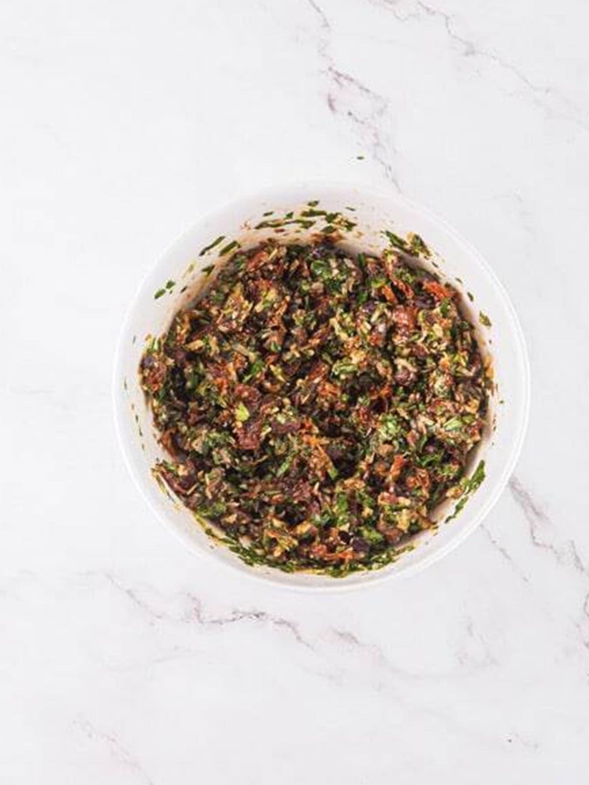 Mediterranean dip mixed together in a white bowl ready to serve.