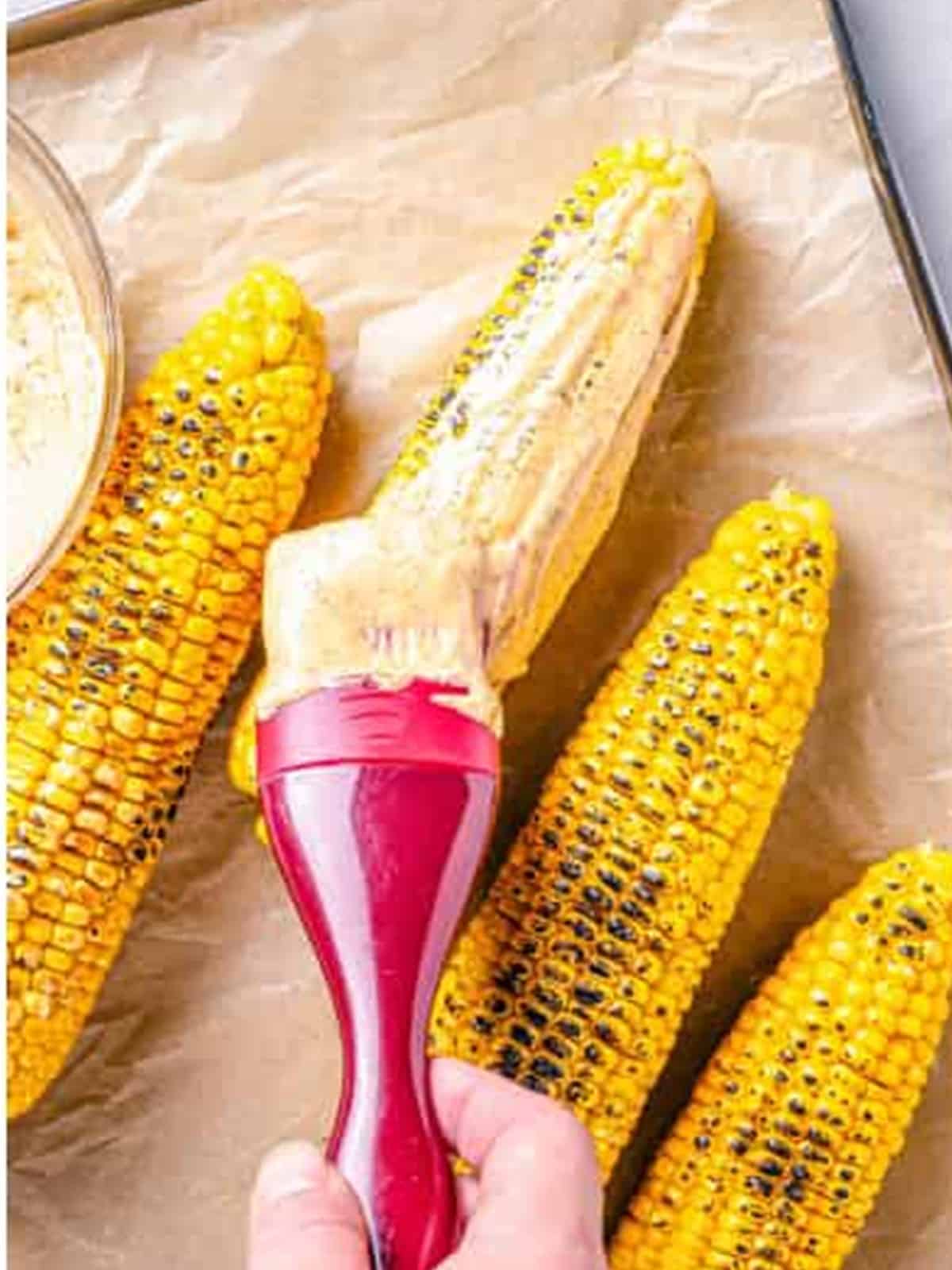 Brushing chipotle mayo all over the grilled corn.