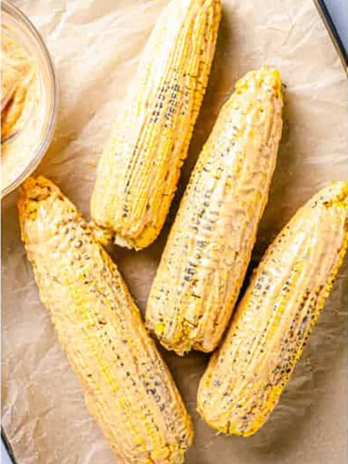 Grilled corn coated in chipotle mayo before adding cheese.