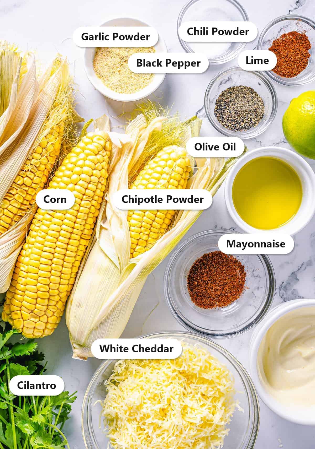 Labeled ingredients for Mexican street corn including corn, white cheddar, mayonnaise, chipotle powder, chili powder, garlic powder, lime, and cilantro.