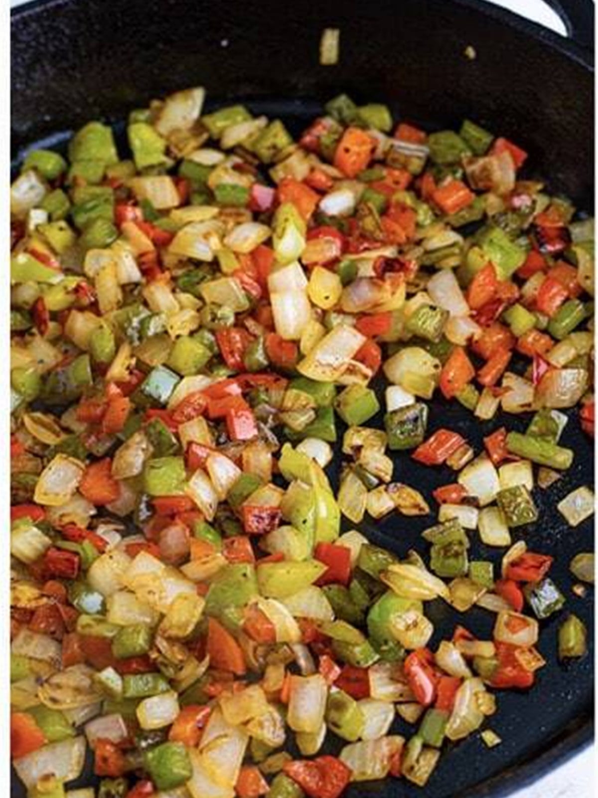 Sauteing diced bell peppers and onion in a skillet for migas.