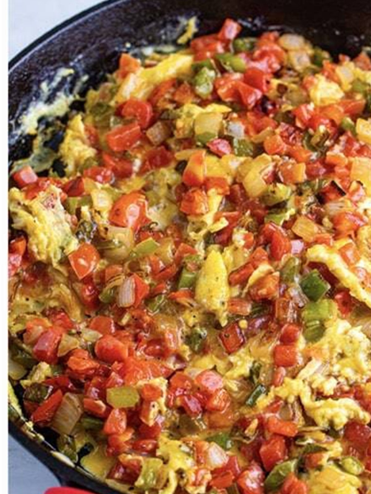 Scrambling eggs into the peppers and tomatoes for migas.