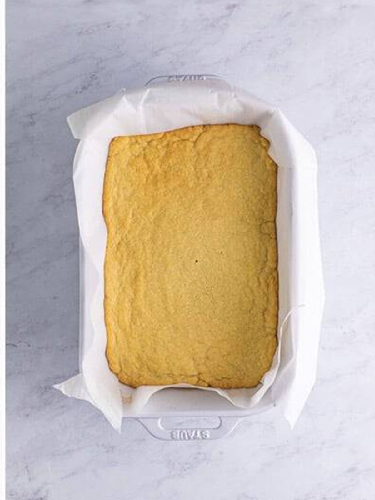 Baked golden shortbread base in a parchment-lined pan.