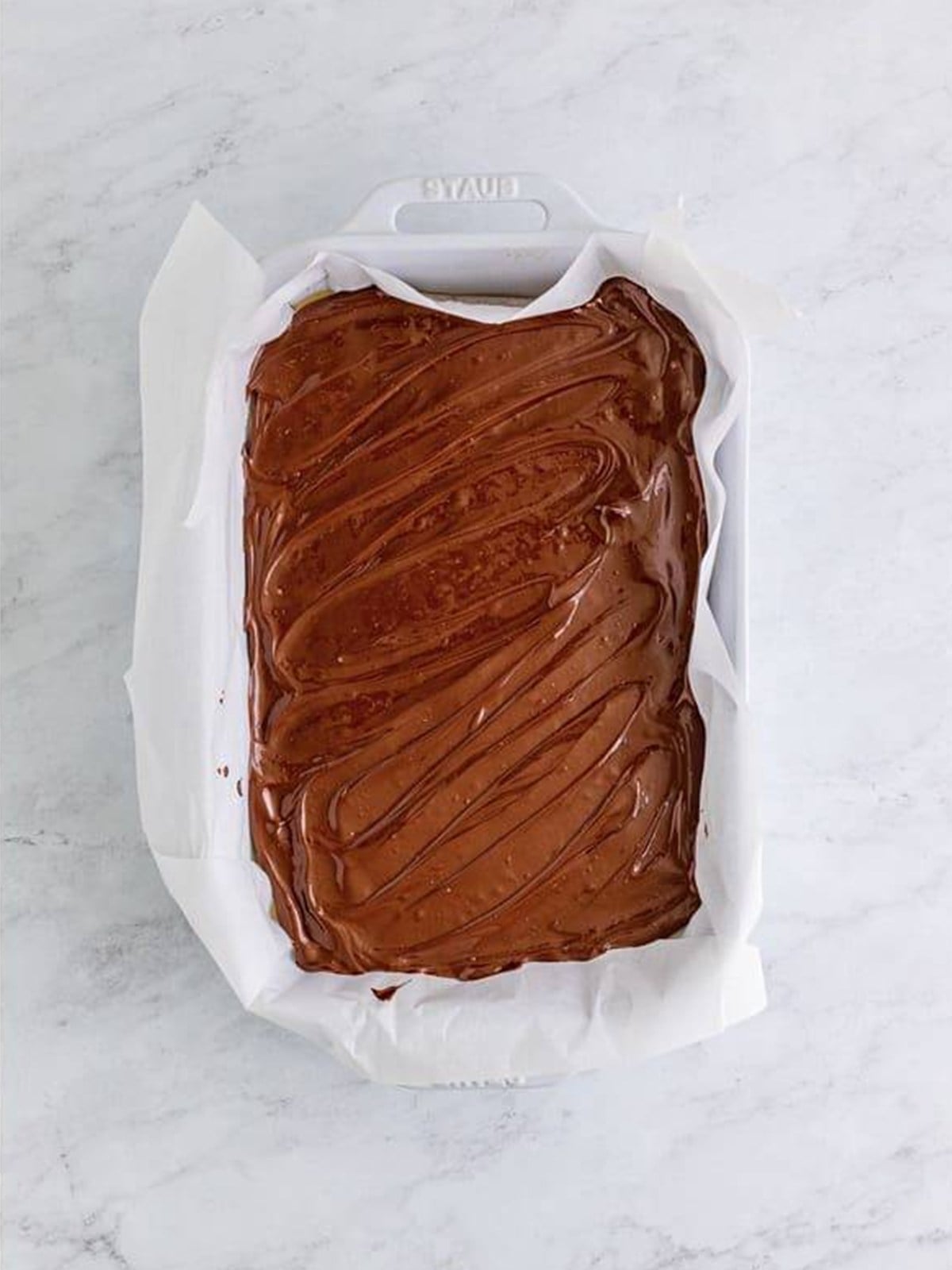 Smooth melted chocolate spread over the caramel layer of millionaires shortbread.