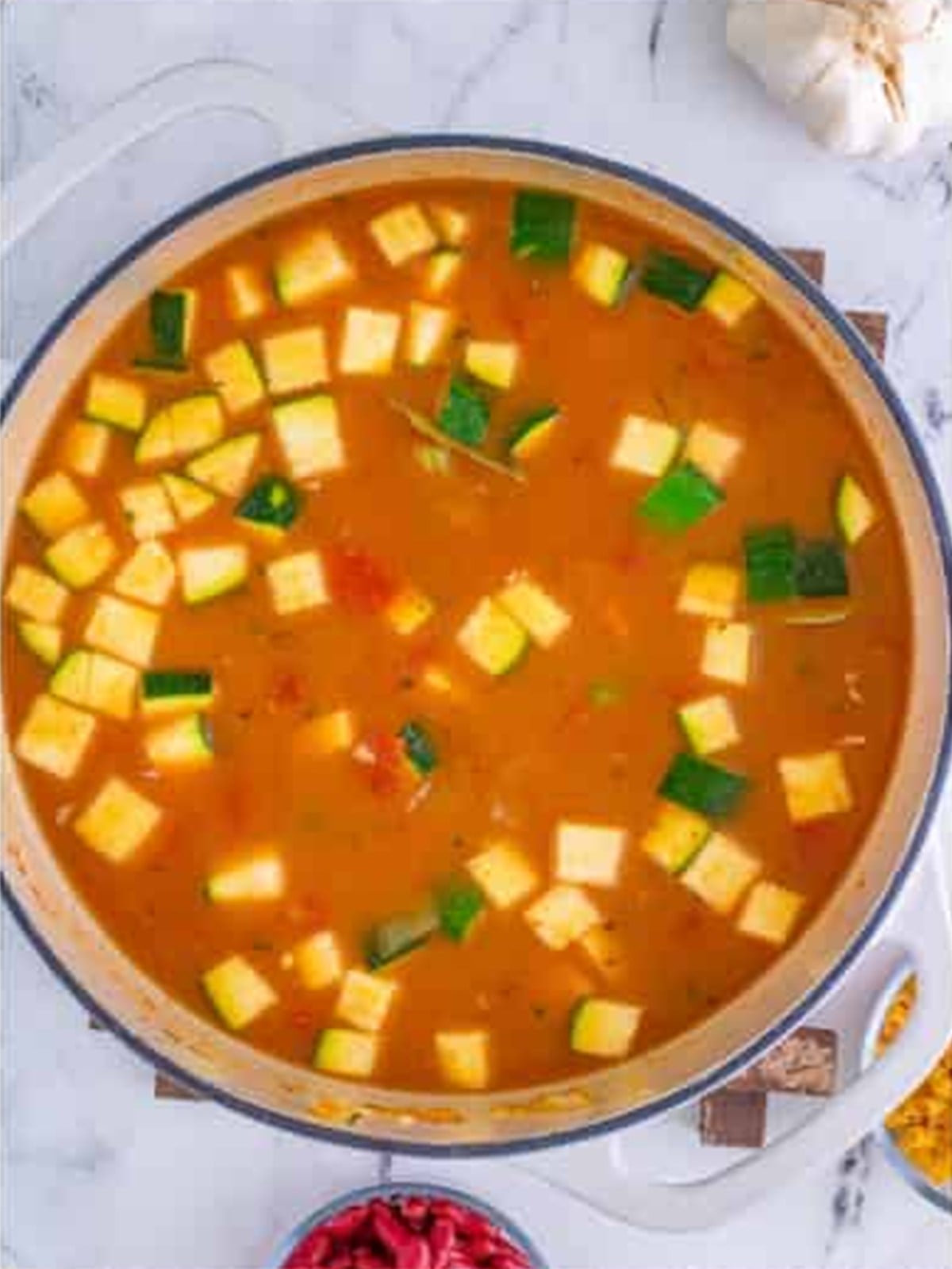 Vegetable broth and diced tomatoes added to the pot of minestrone soup.