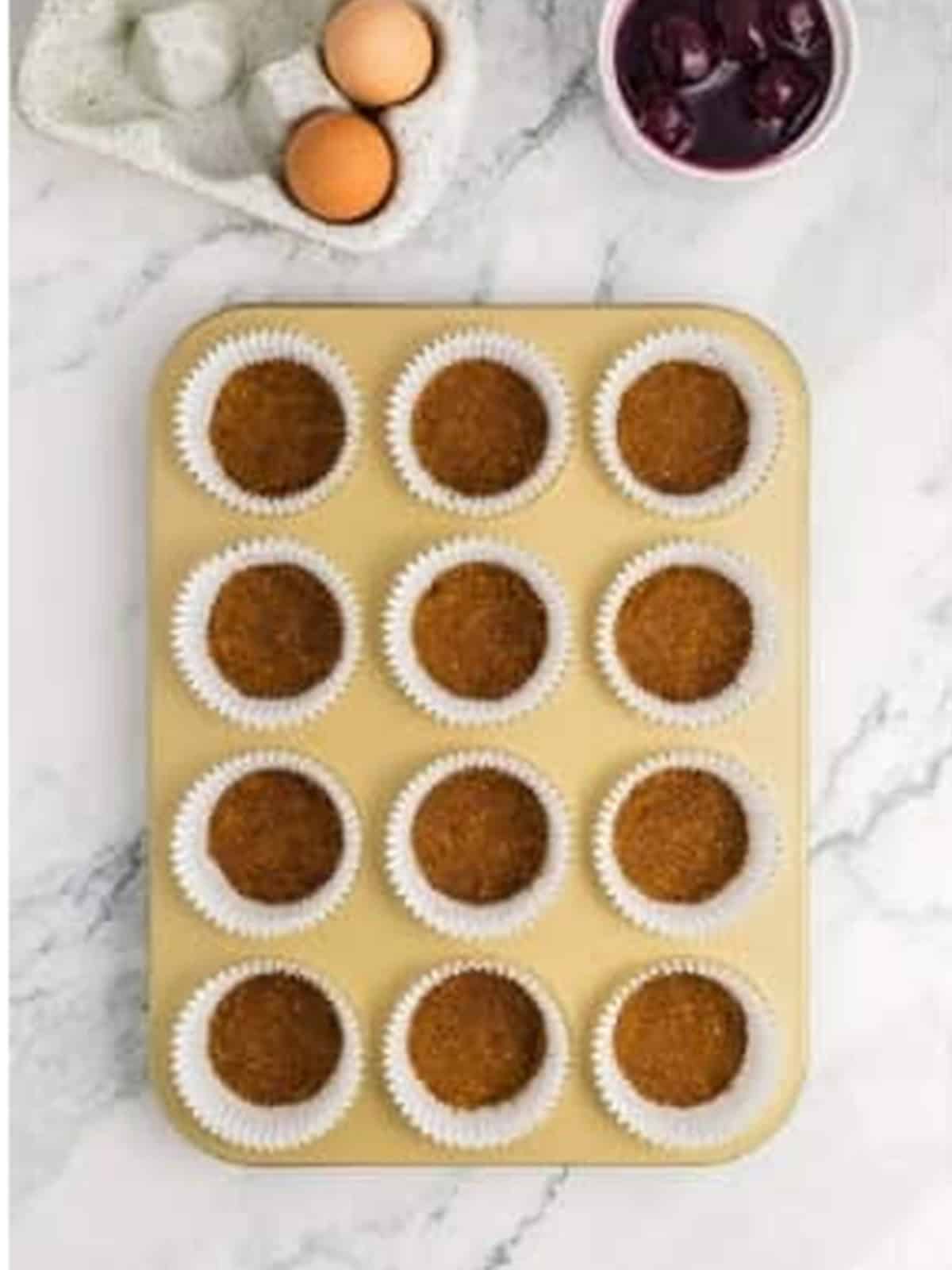 Graham cracker crust pressed into muffin tin liners.