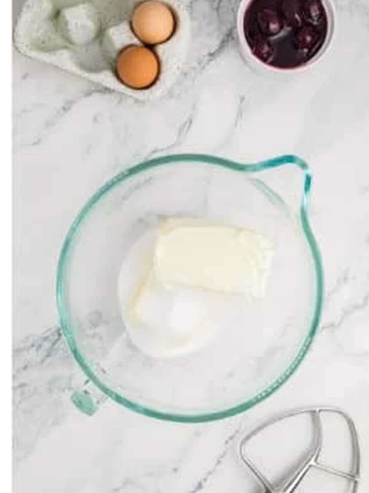 Cream cheese and sugar in a stand mixer bowl for cheesecake filling.