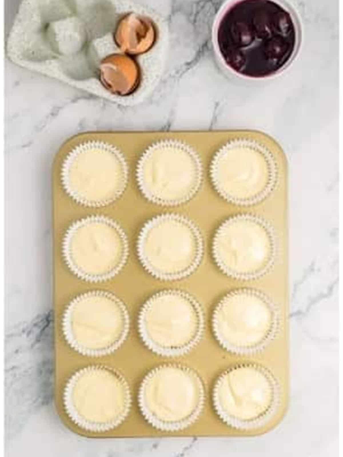 Cheesecake filling divided into muffin tin liners.