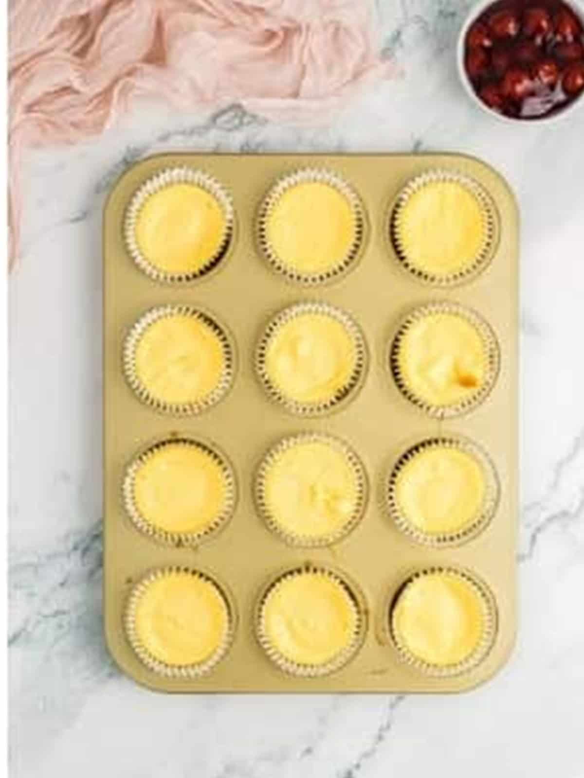 Baked mini cheesecakes in a muffin tin.