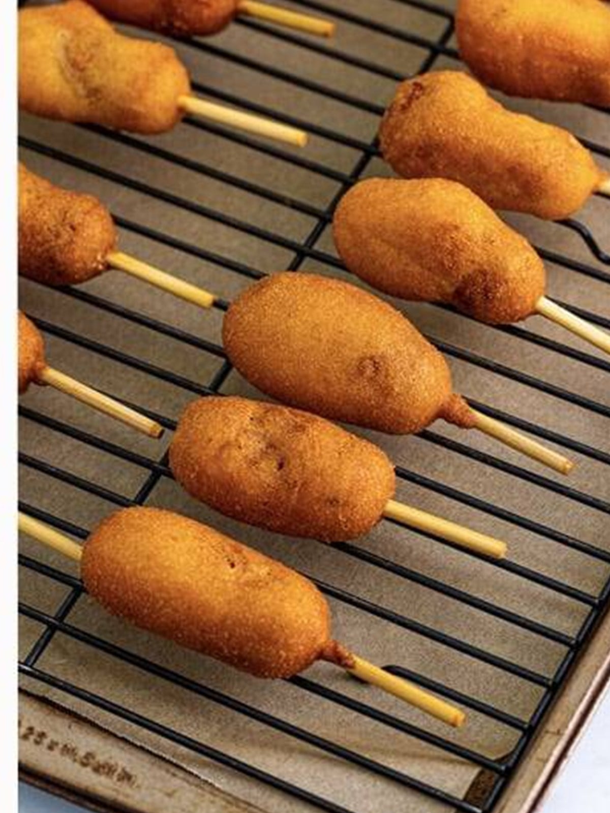 Golden fried mini corn dogs draining on a wire rack.