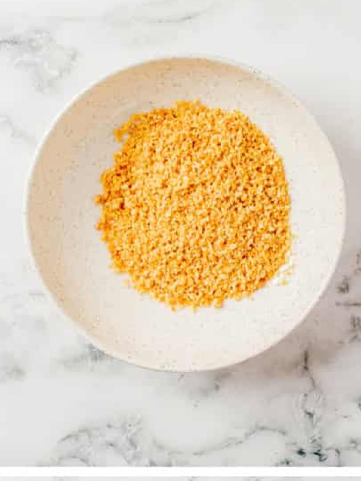 Garlic butter croutons crushed into fine crumbs in a bowl.