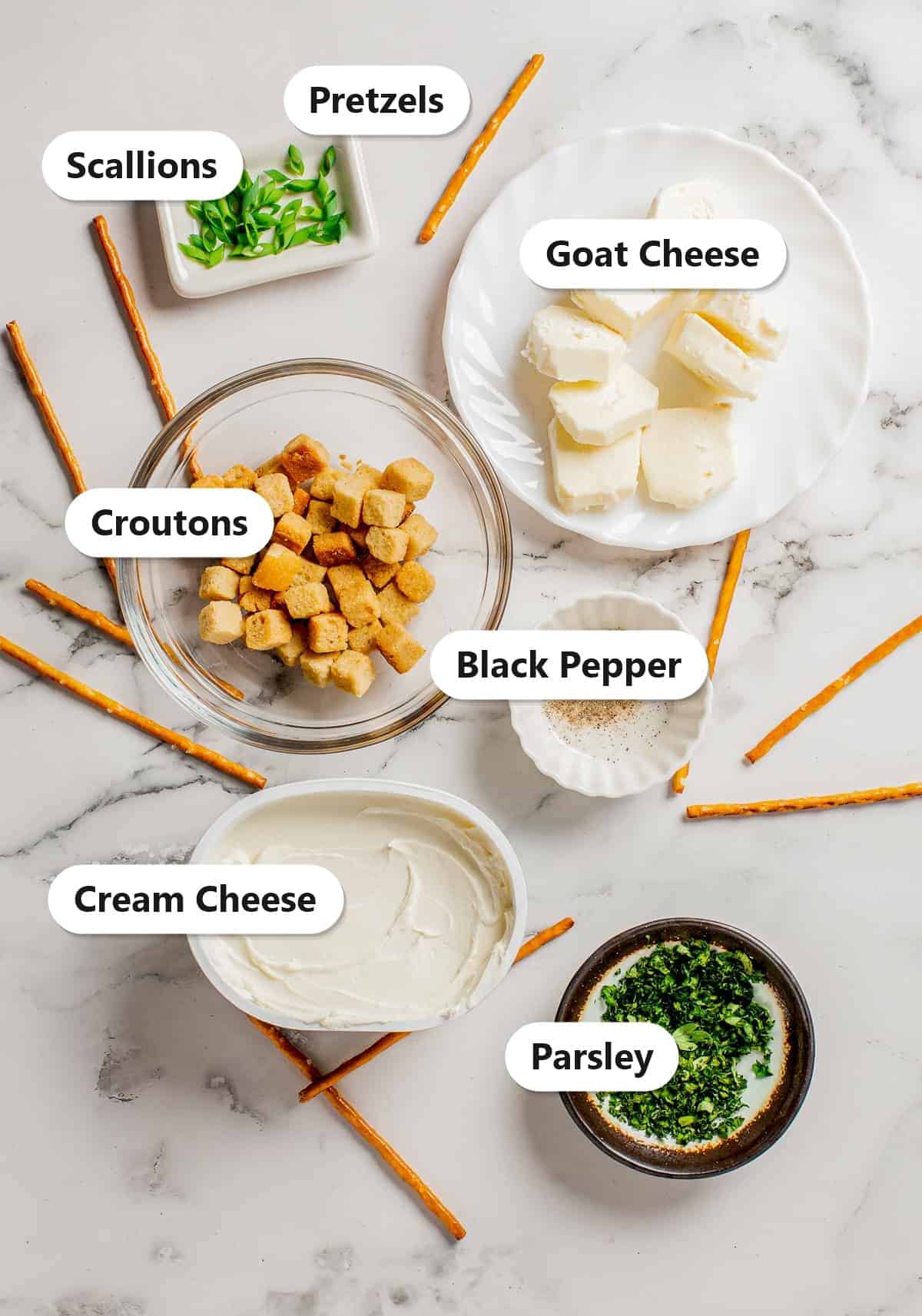 Labeled ingredients for mini goat cheese balls including scallions, pretzels, goat cheese, croutons, black pepper, cream cheese, and parsley.
