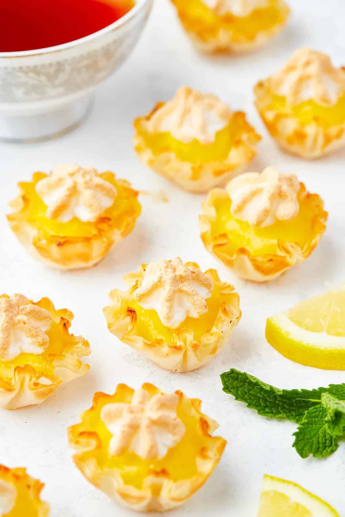 Mini lemon meringue pies with golden toasted meringue scattered with fresh lemon.