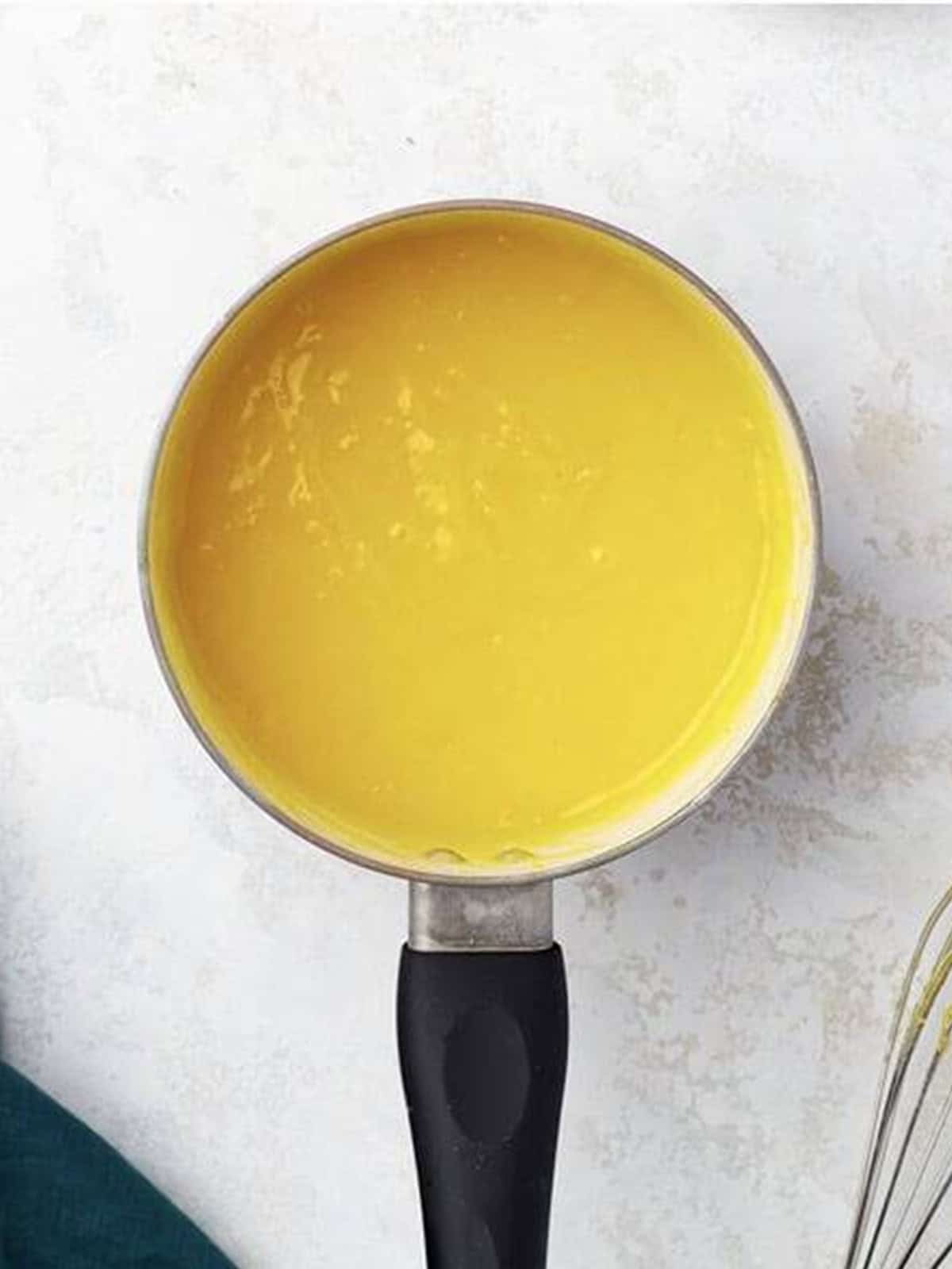Thickened lemon curd filling in a saucepan.