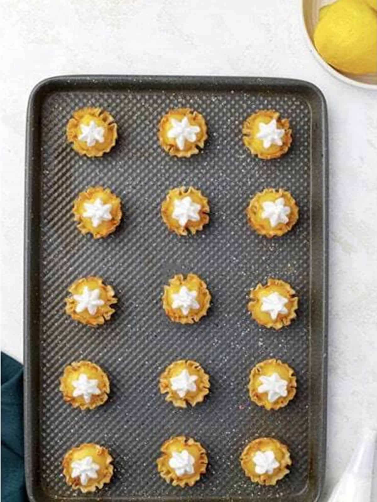 Mini lemon meringue pies topped with piped meringue before baking.