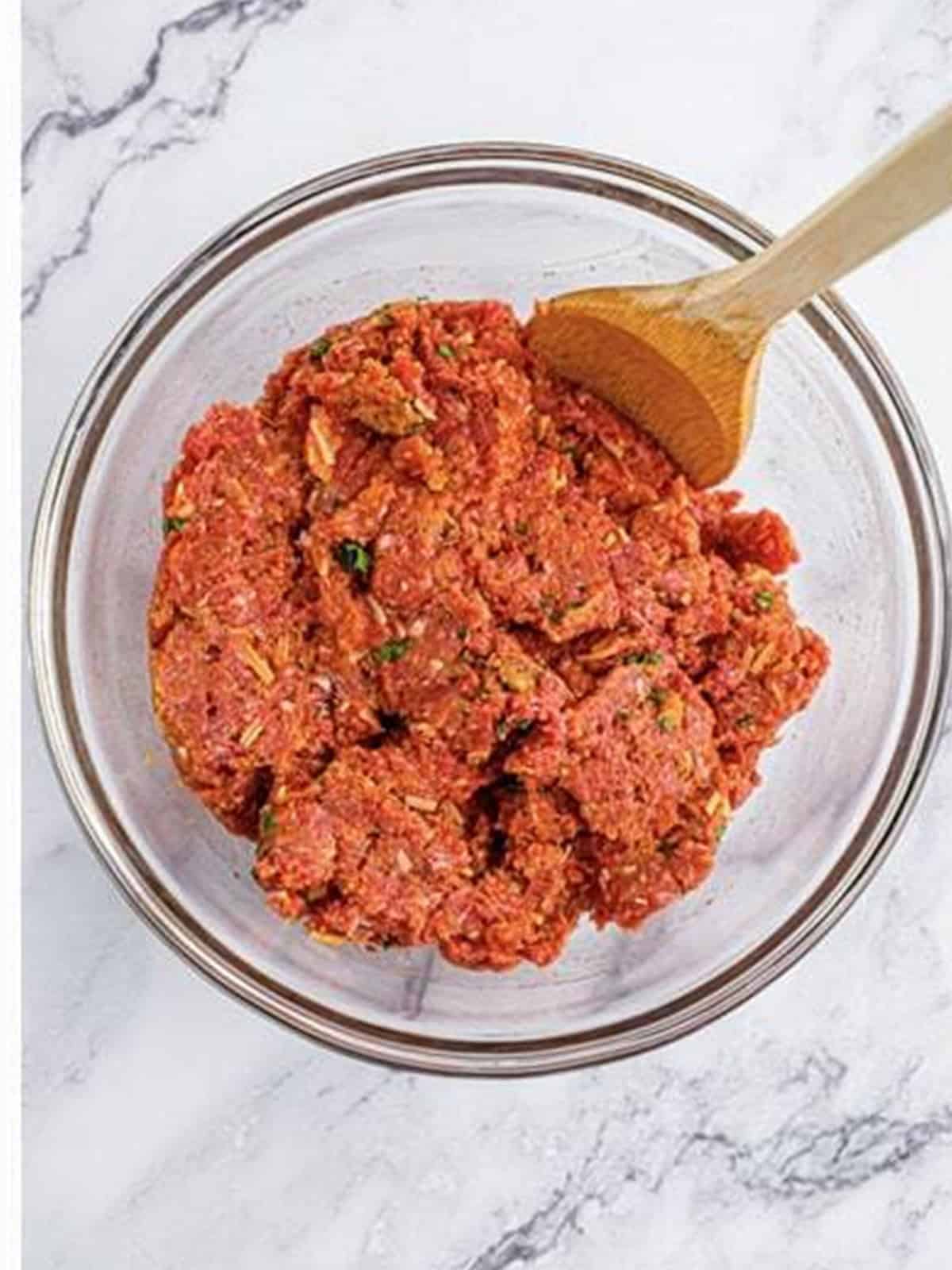 Ground beef mixed with marinara, breadcrumbs, parmesan, and egg in a bowl for mini meatloaf.