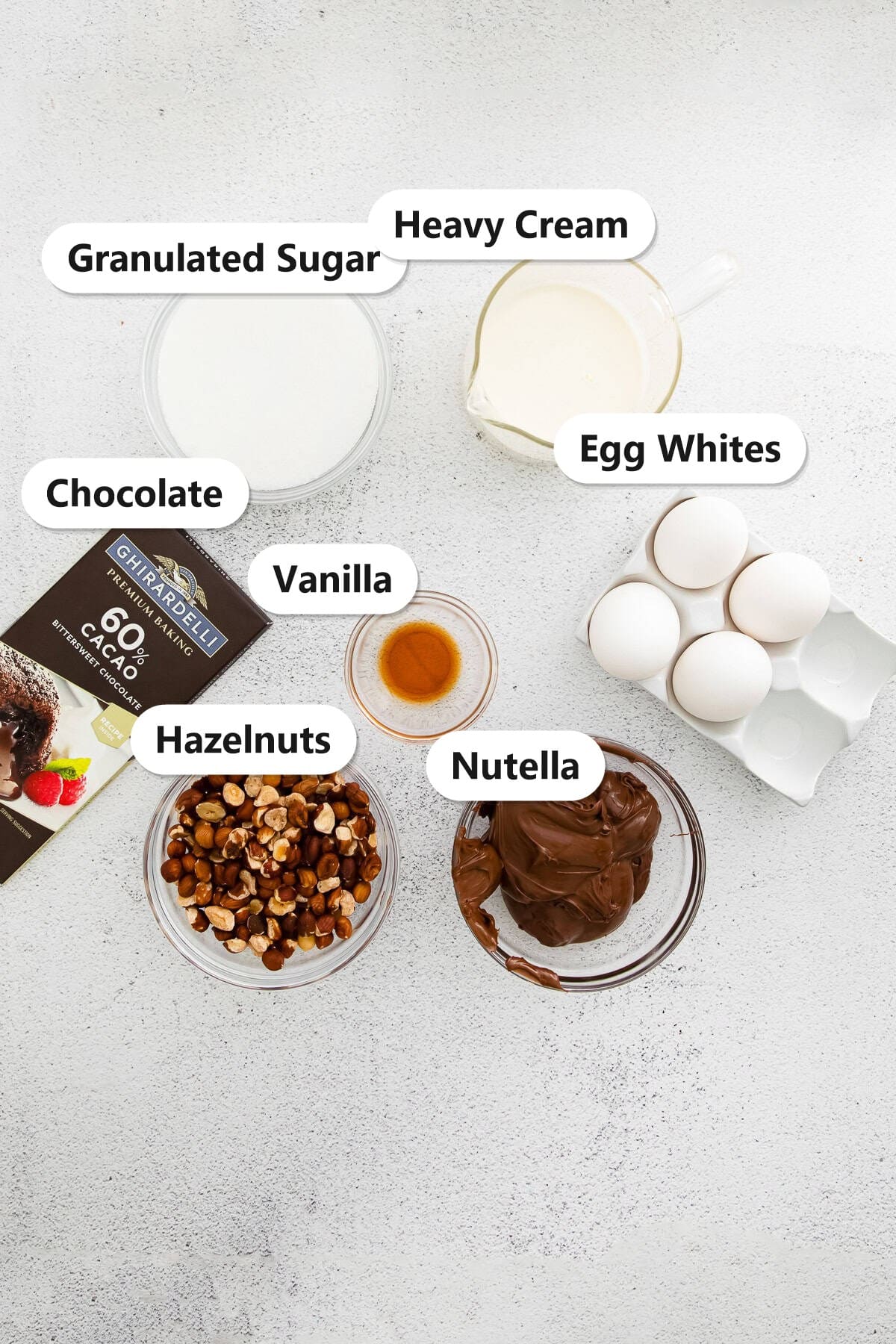 Labeled ingredients for mini pavlova including granulated sugar, heavy cream, egg whites, chocolate, vanilla, hazelnuts, and Nutella.