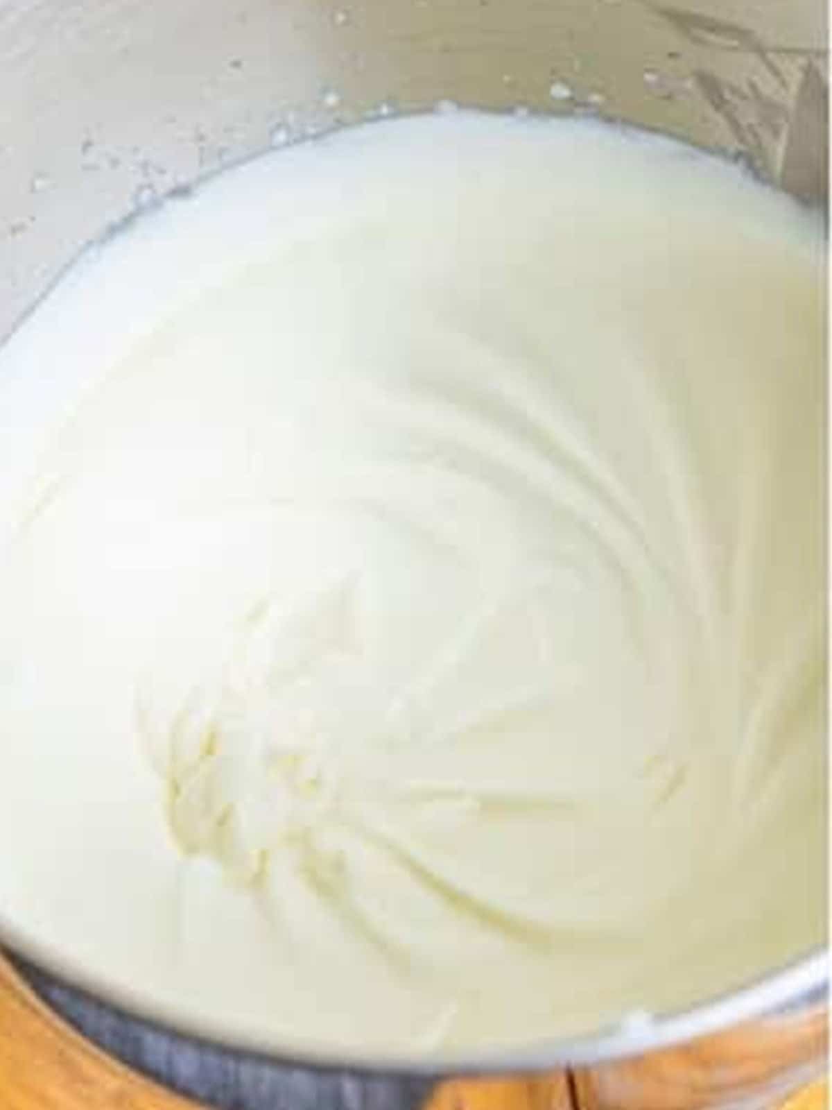 Heavy whipping cream whipped to soft peaks in a metal bowl.