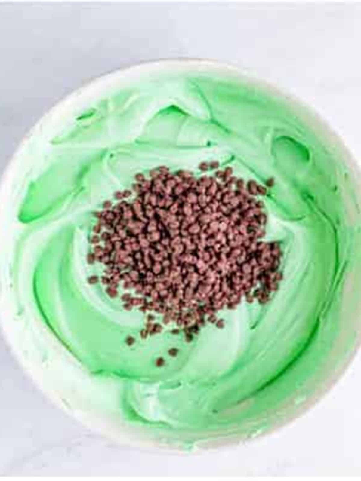 Green tinted mint cheesecake filling with mini chocolate chips being folded in.