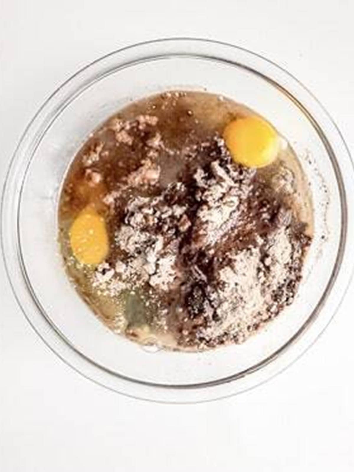 Fudge brownie mix combined with eggs and oil in a glass bowl.