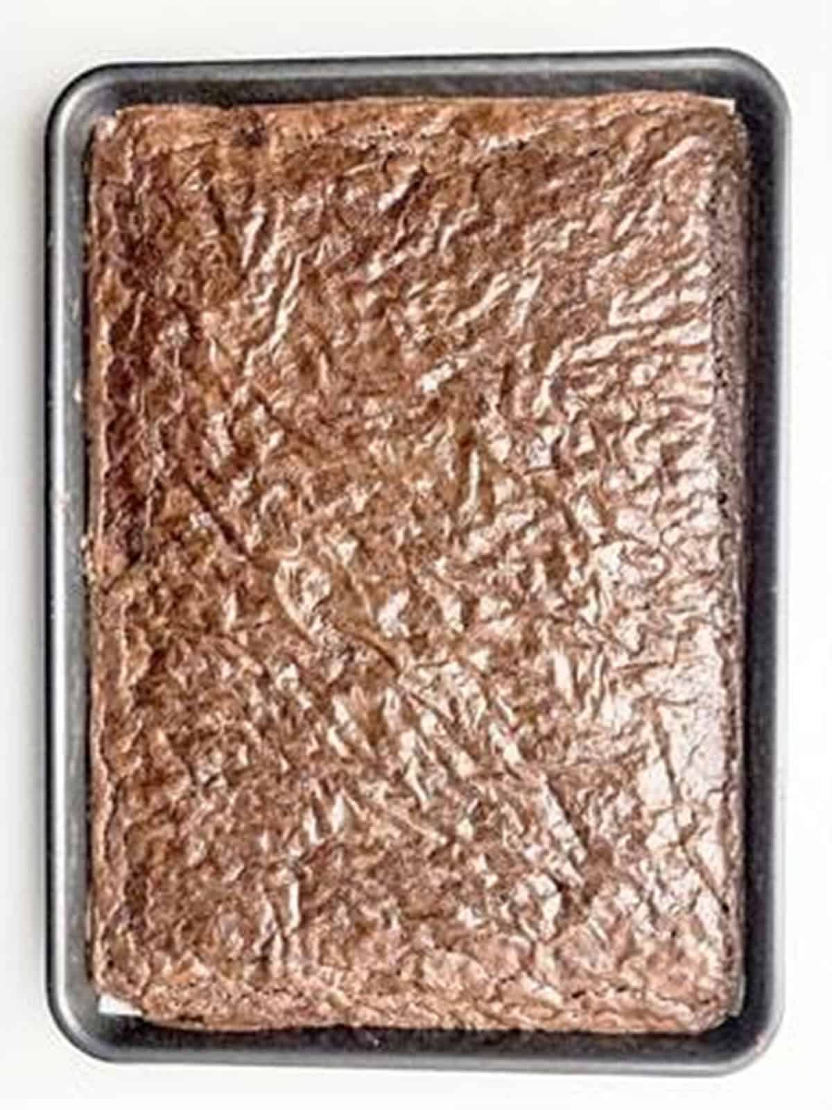 Baked brownie layer in a parchment lined baking pan.