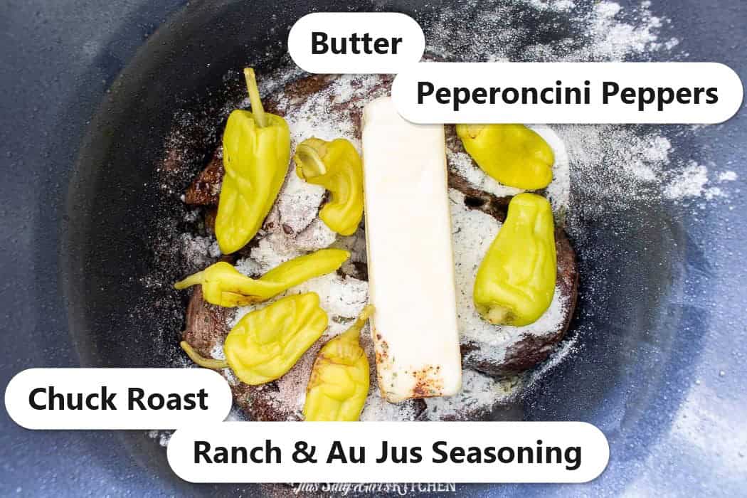 Mississippi pot roast ingredients in a slow cooker including chuck roast, butter, peperoncini peppers, and ranch and au jus seasoning.
