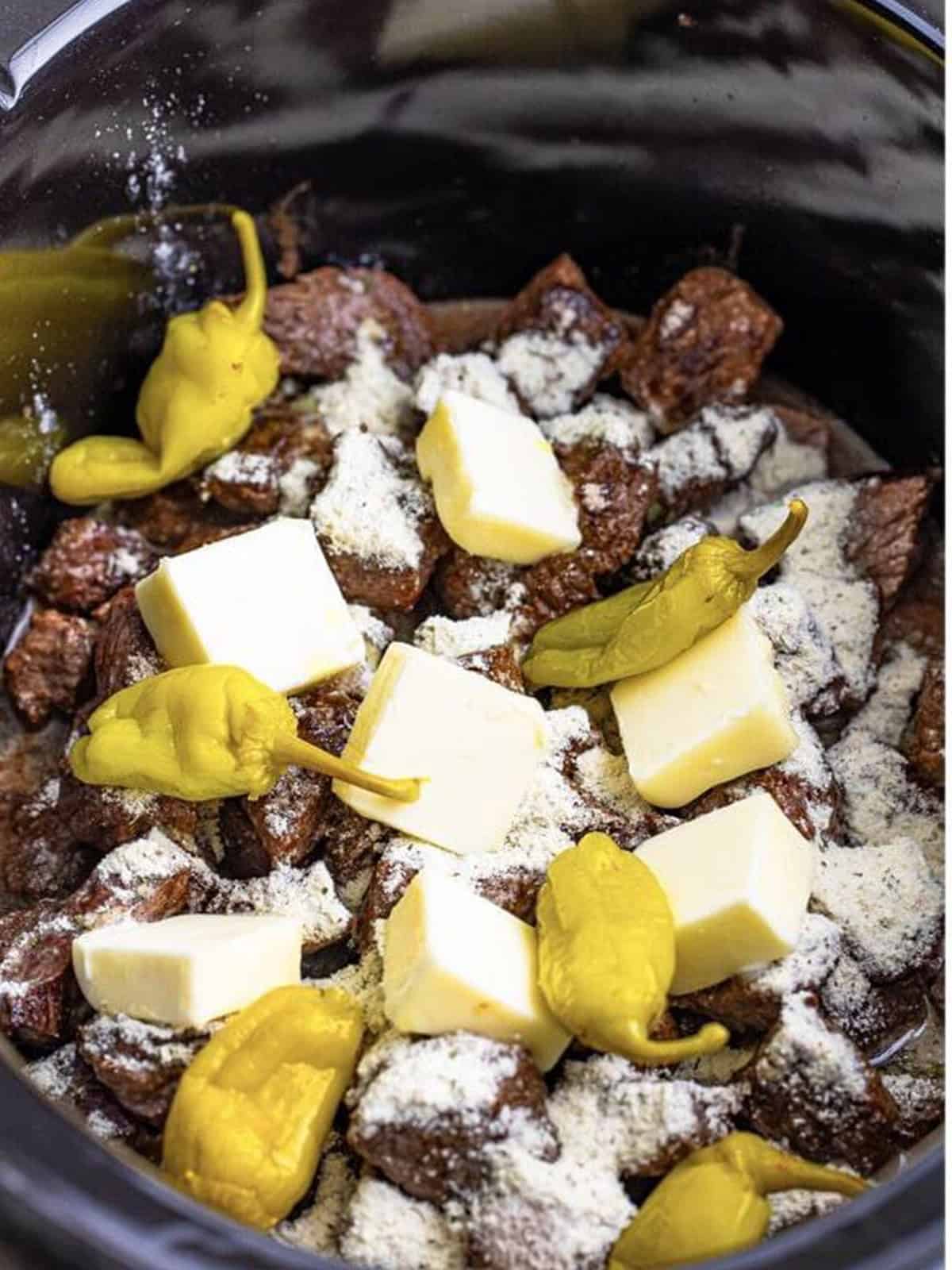 Pepperoncini peppers added on top of the buttery seasoned steak bites before cooking.