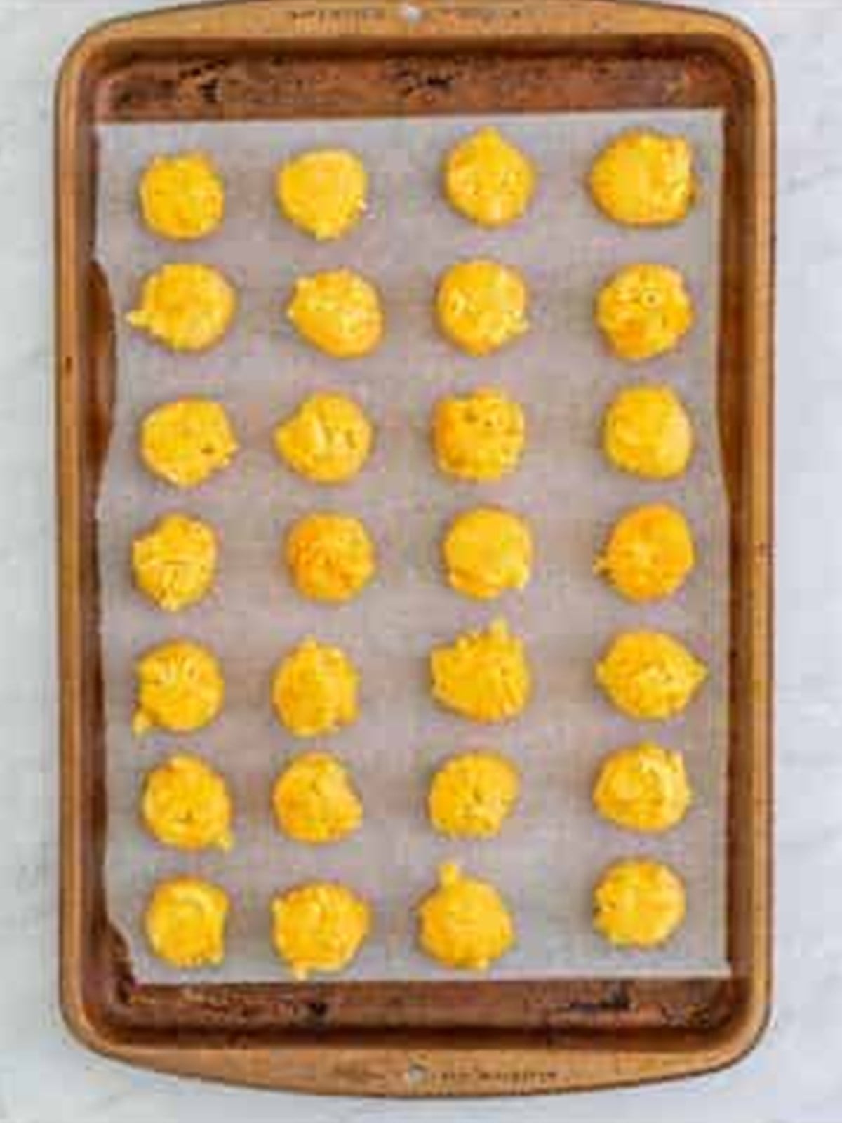 Chilled mac and cheese rolled into balls on a sheet tray.