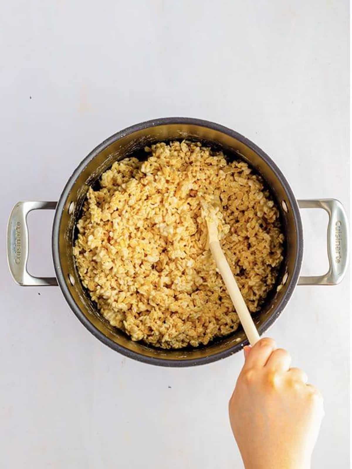 Rice Krispies cereal stirred into melted marshmallows in a pot.