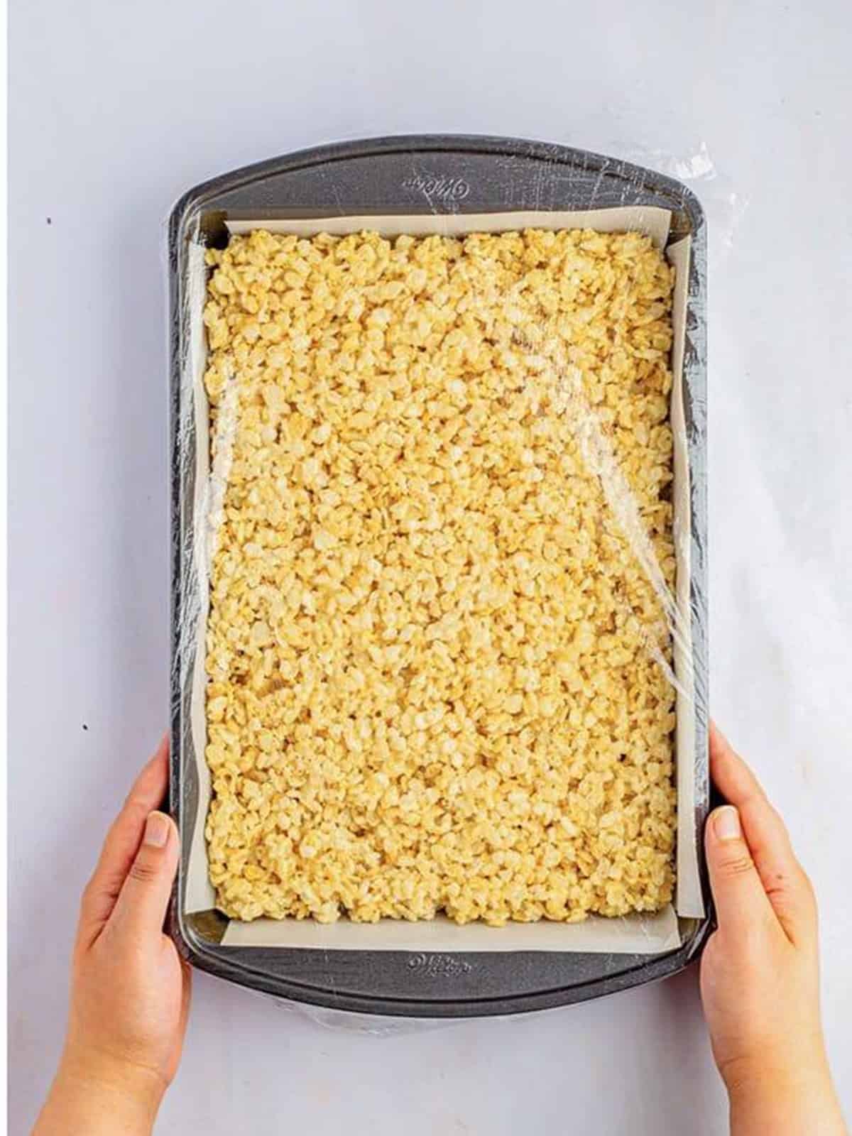 Rice krispie treat mixture pressed into a parchment lined pan.