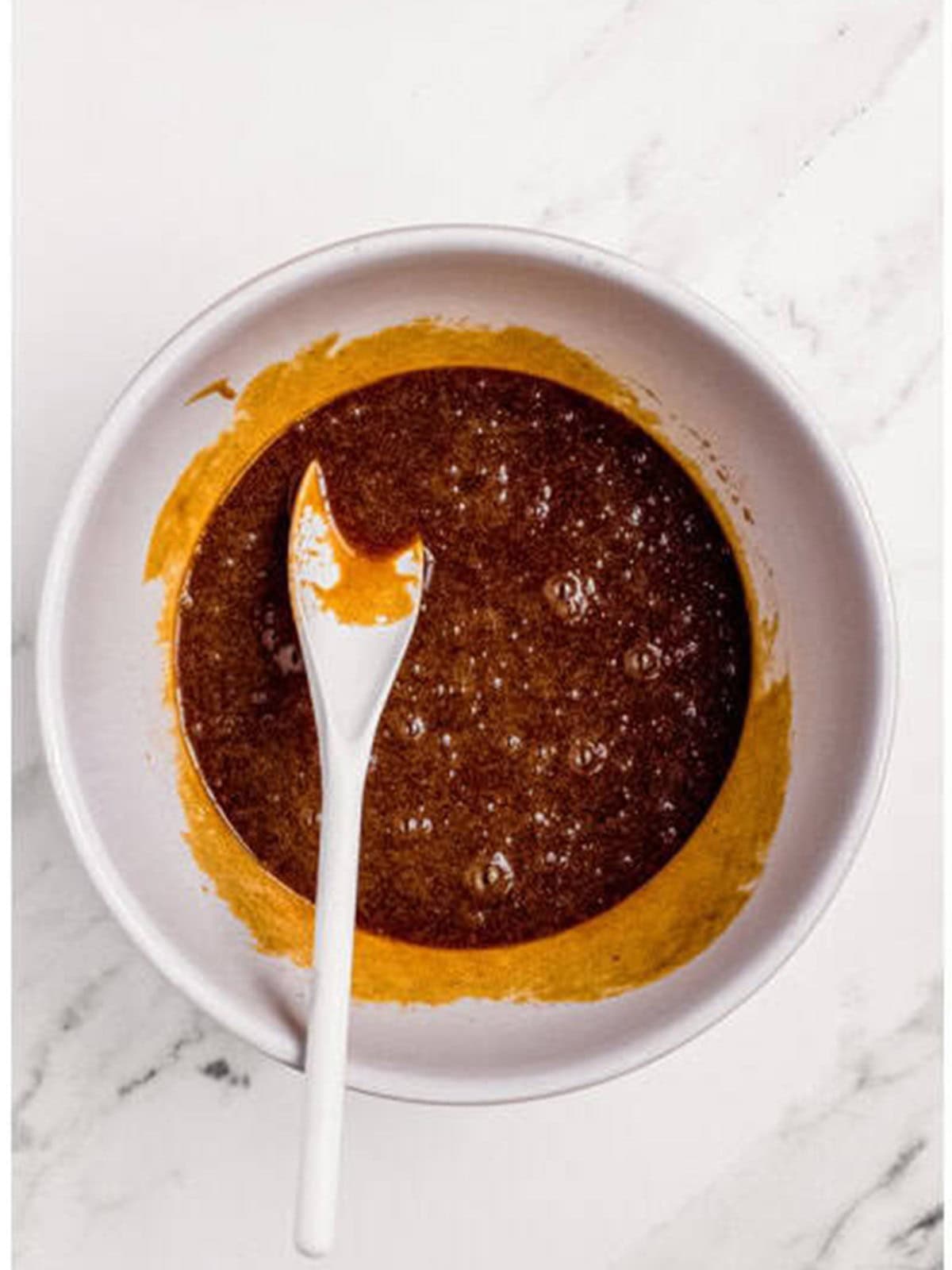 Beating butter, brown sugar, and molasses together in a bowl for molasses cookies.