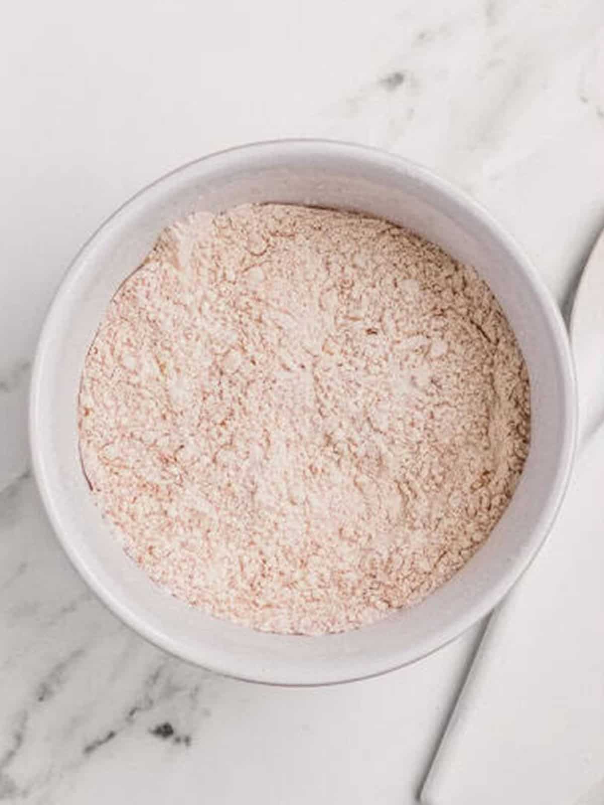 Whisked flour, spices, and baking soda in a bowl for molasses cookies.