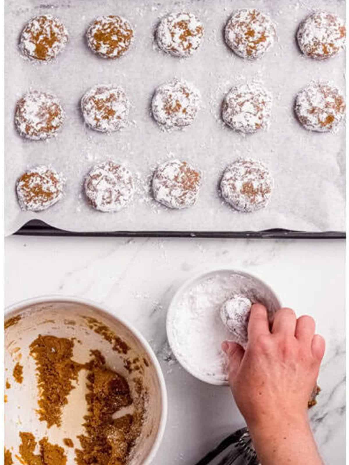 Rolling molasses cookie dough balls in powdered sugar.