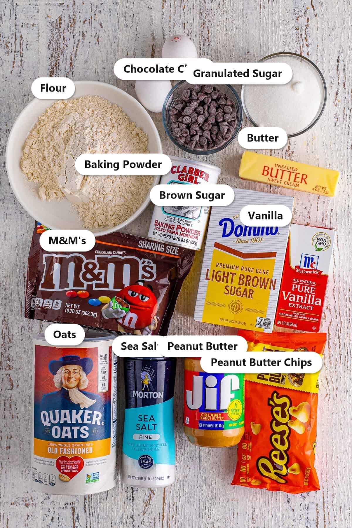 Labeled ingredients for monster cookie bars including flour, oats, peanut butter, M and Ms, chocolate chips, and sugars.