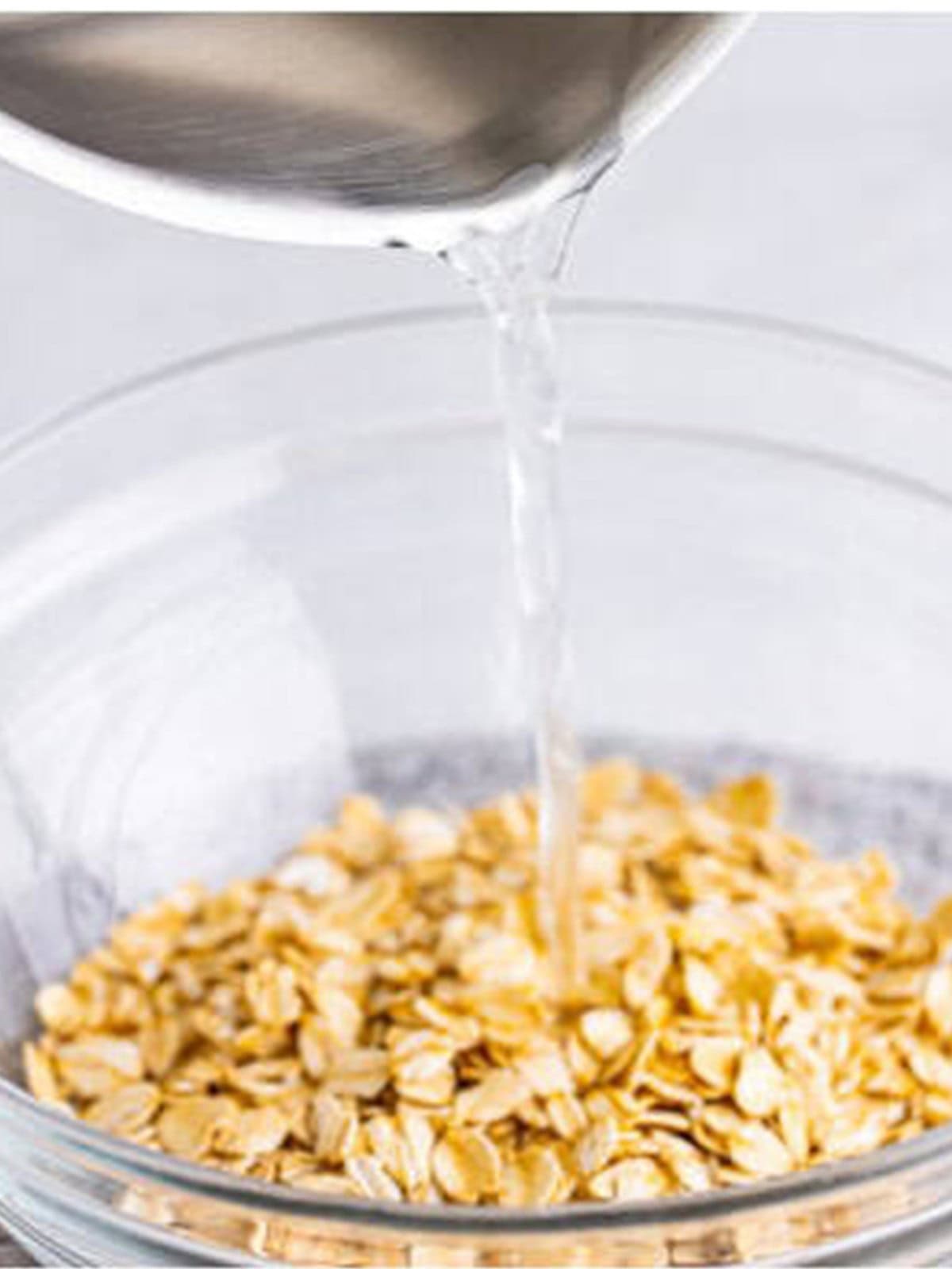 Boiling water poured over old fashioned oats in a glass bowl.
