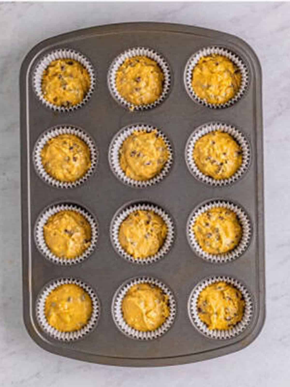 Batter divided between twelve cupcake liners in the tin.
