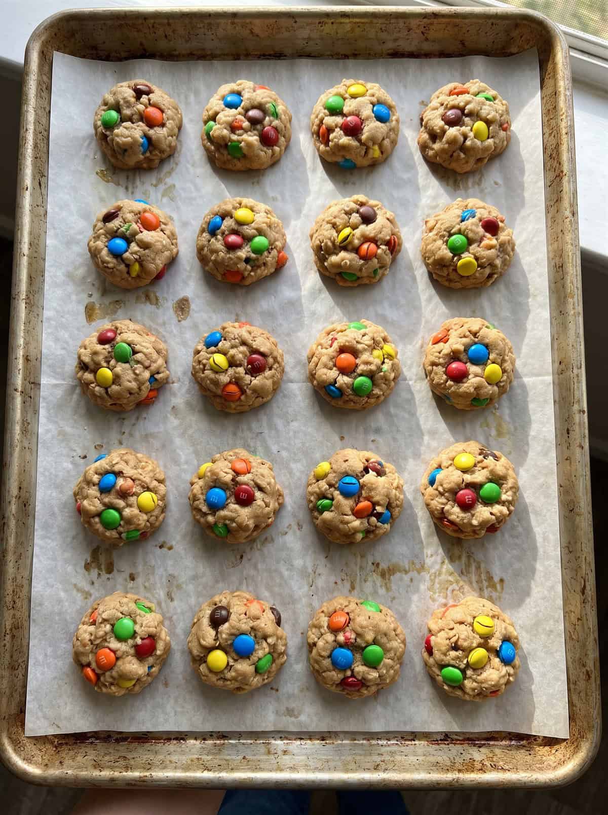 Freshly baked mini monster cookies on a baking sheet.